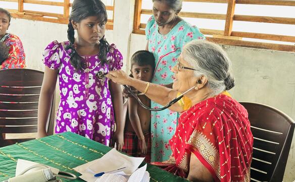 Eine Frau hört mit einem Stetoskop den Brustraum eines Mädchens ab
