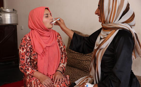 Eine Frau misst einer anderen mit einem Fieberthermometer im Mund die Temperatur