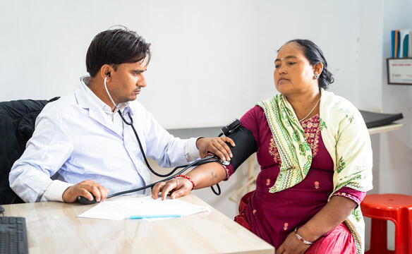 Ein Arzt misst bei einer Patientin Blutdruck