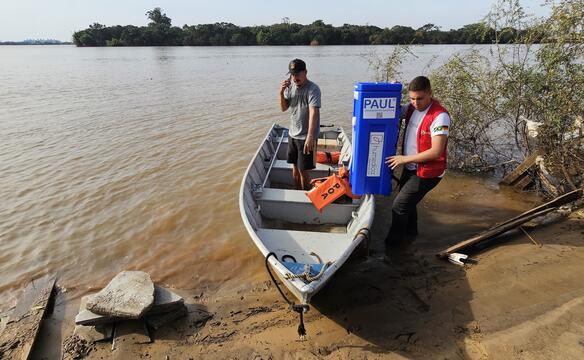humedica employees transport a water filter by boat to a flooded area