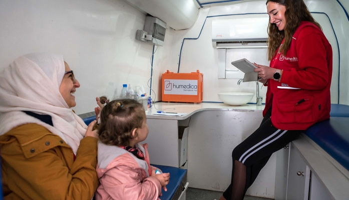 Gespräch zwischen Frau mit Tochter und humedica-Mitarbeiterin in mobiler Klinik